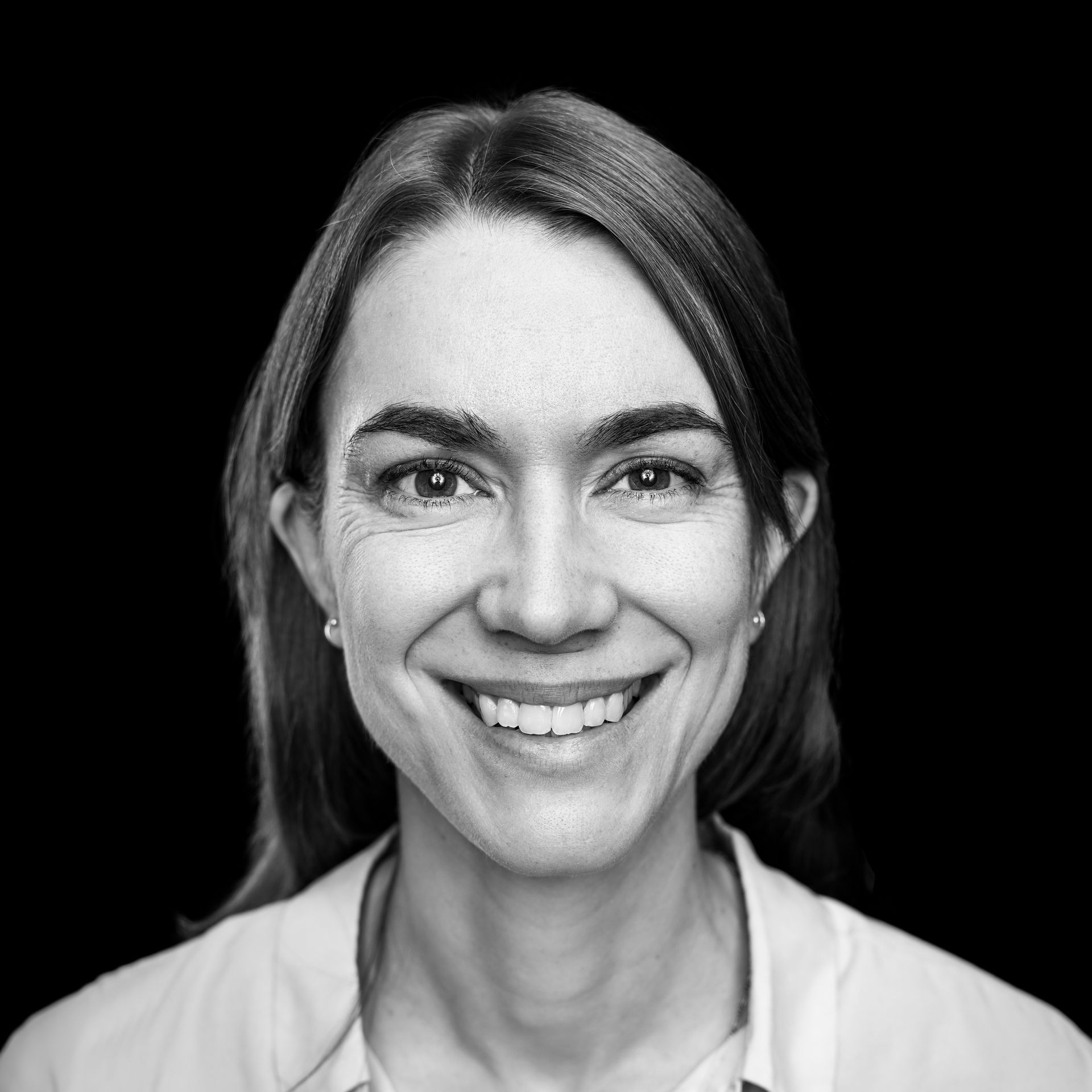 A woman is smiling in a black and white photo.