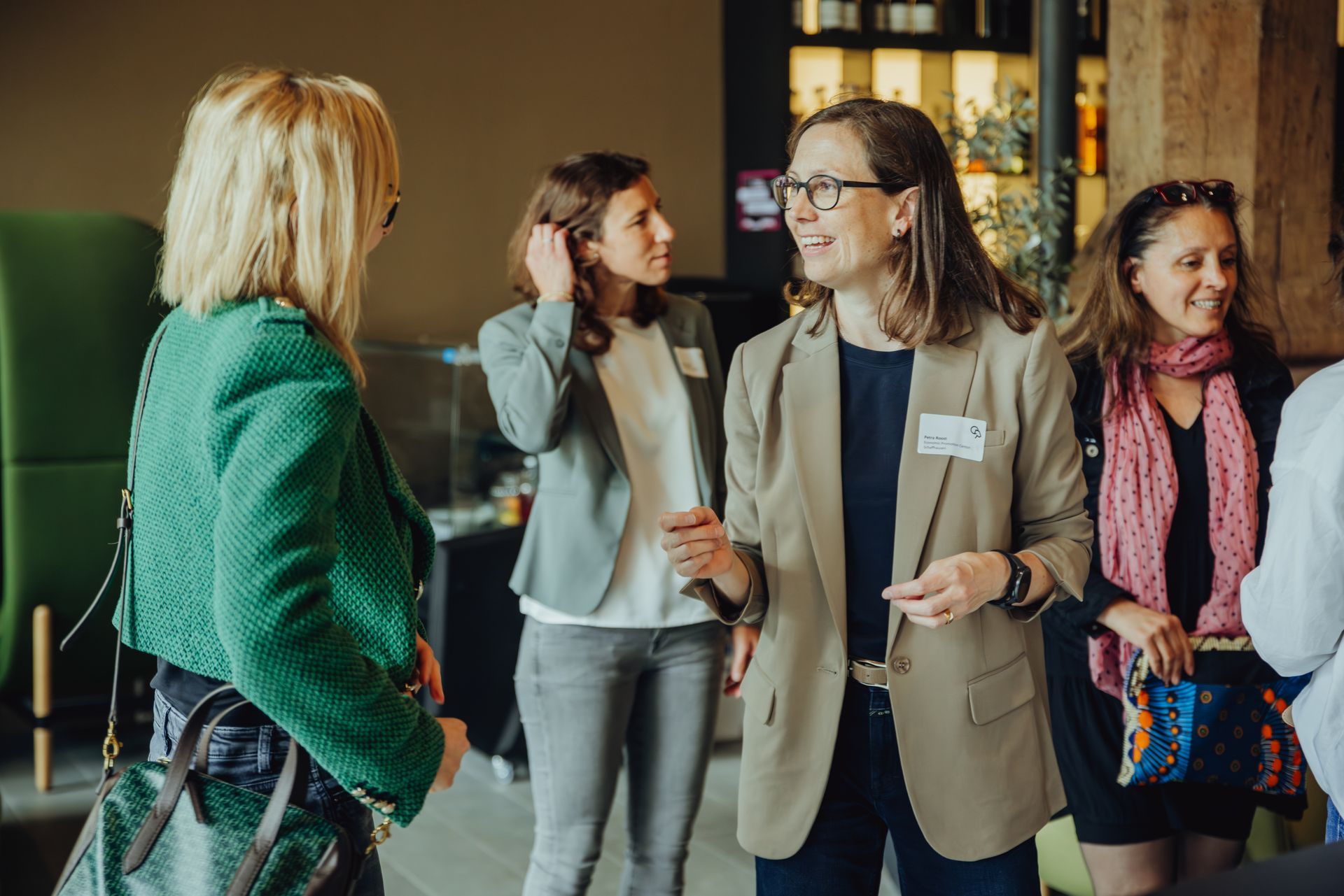 A group of women are standing next to each other and talking in a room.