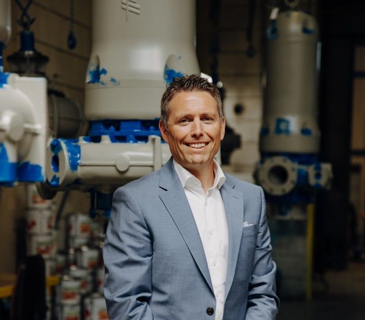 A man in a suit is standing in front of some pipes