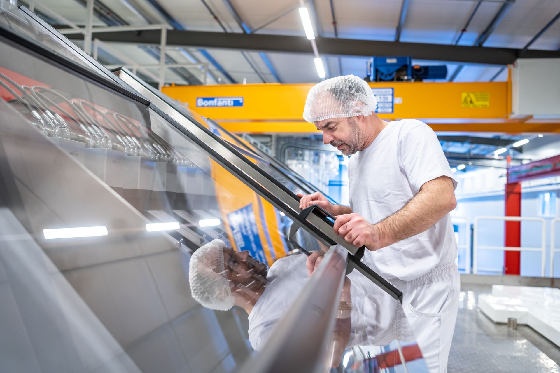 A man in a white uniform is working on a butter press in the Pronatec factory.