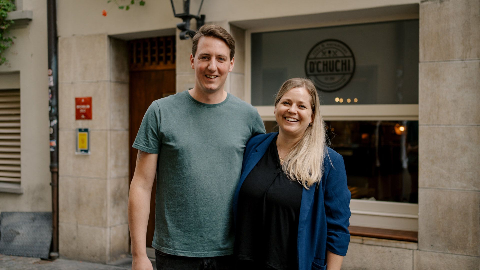 A man and a woman are standing in front of a building.